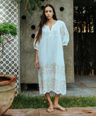 A model wearing a Rose and Rose Grange dress in White with sand appliqué decoration.