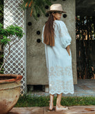 A back view of a model wearing a Rose and Rose Grange dress in white with sand appliqué decoration.