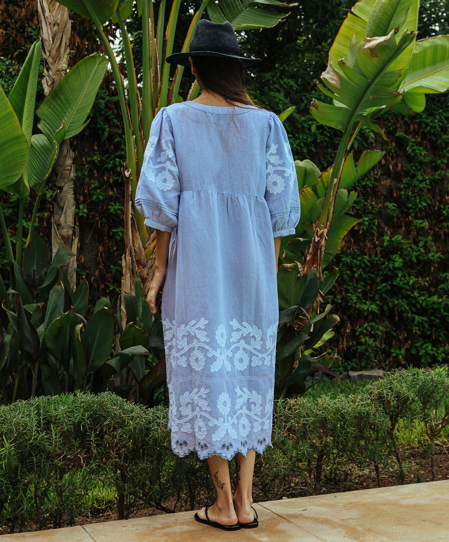 Back view of a model wearing a Rose and Rose Grange embroidered dress in blue linen.