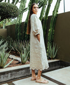 Side view of a model wearing a Rose and Rose Grange embroidered dress in natural linen.