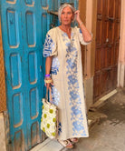 Influencer @simpson.house wearing a Rose natural dress with blue embroidery standing in front of a blue door.