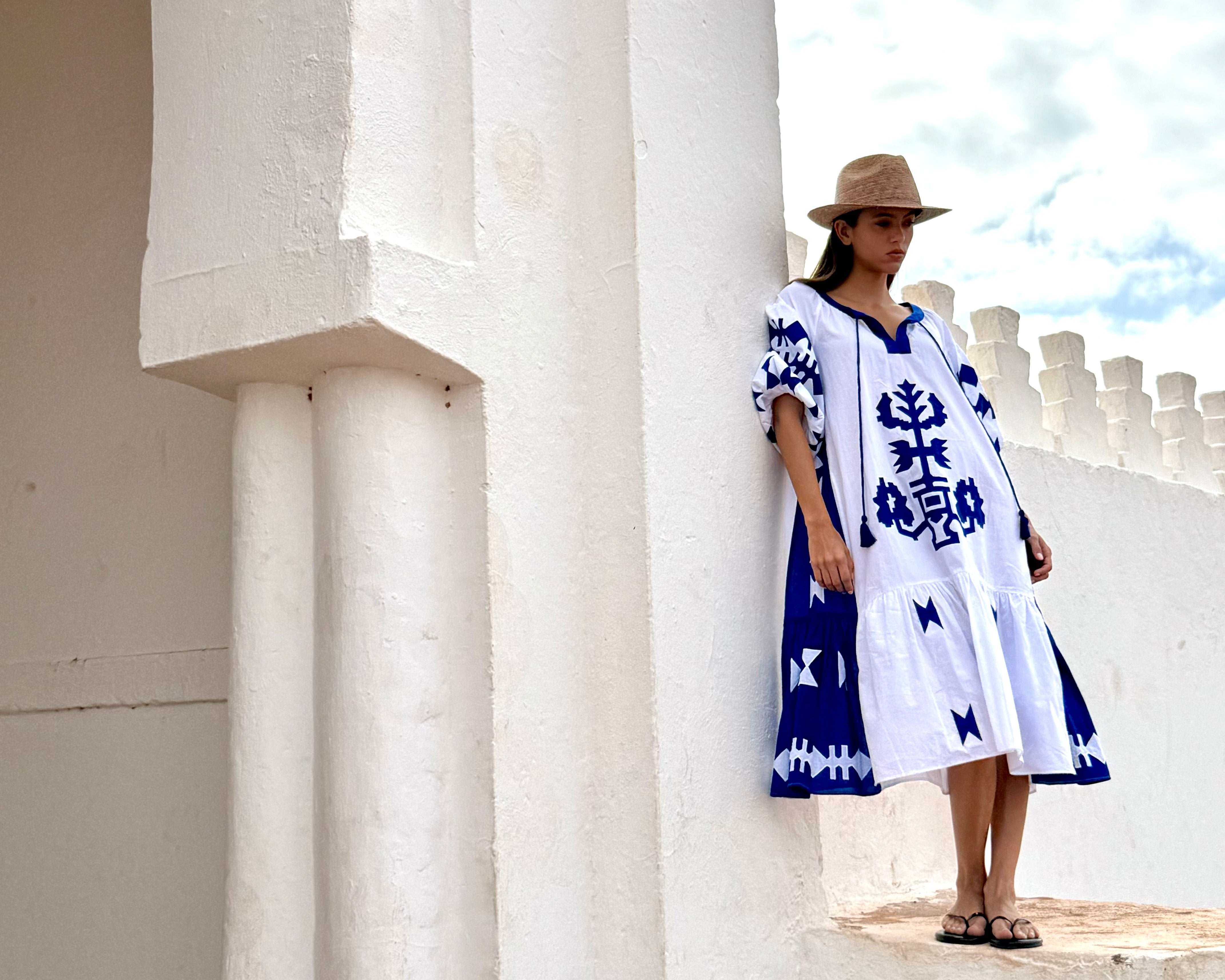 A model wearing a Rose and Rose Amersham dress with a straw hat and flip flops.