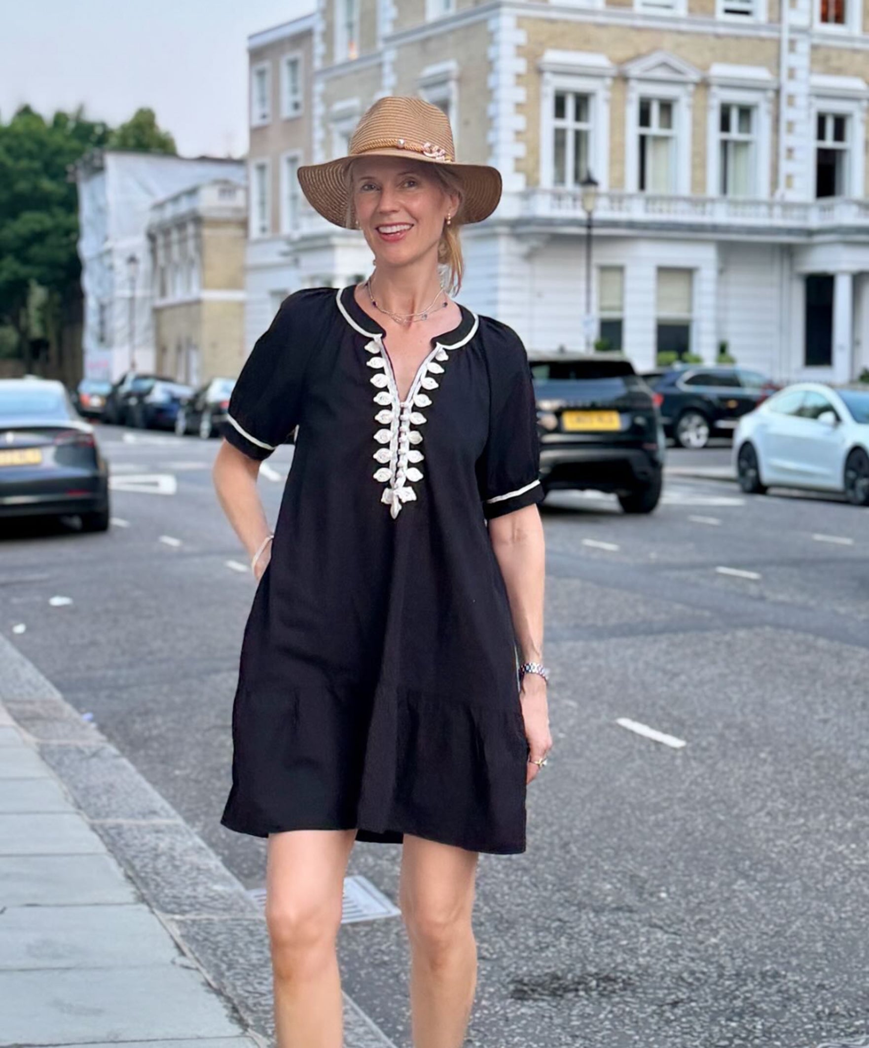 Influencer @swedishgirlinlondon wearing a black Cannes dress with white embroidery in London streets.
