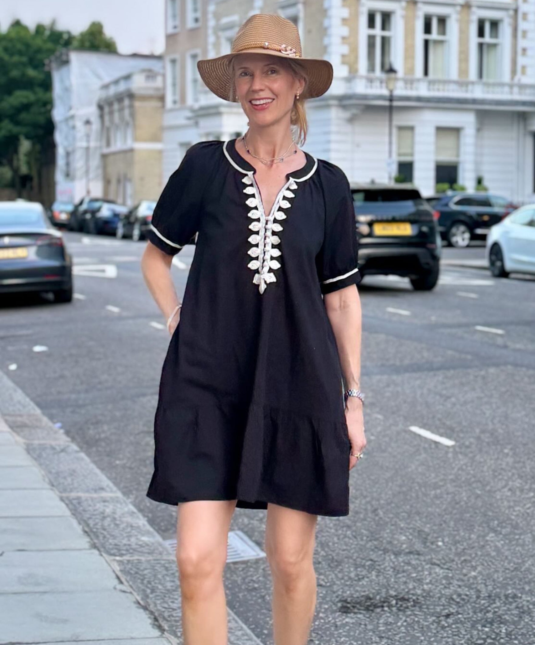 Influencer @swedishgirlinlondon wearing a black Cannes dress with white embroidery in London streets.