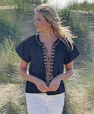 A model on a beach wearing the Rose and Rose Imperia top in black cotton.