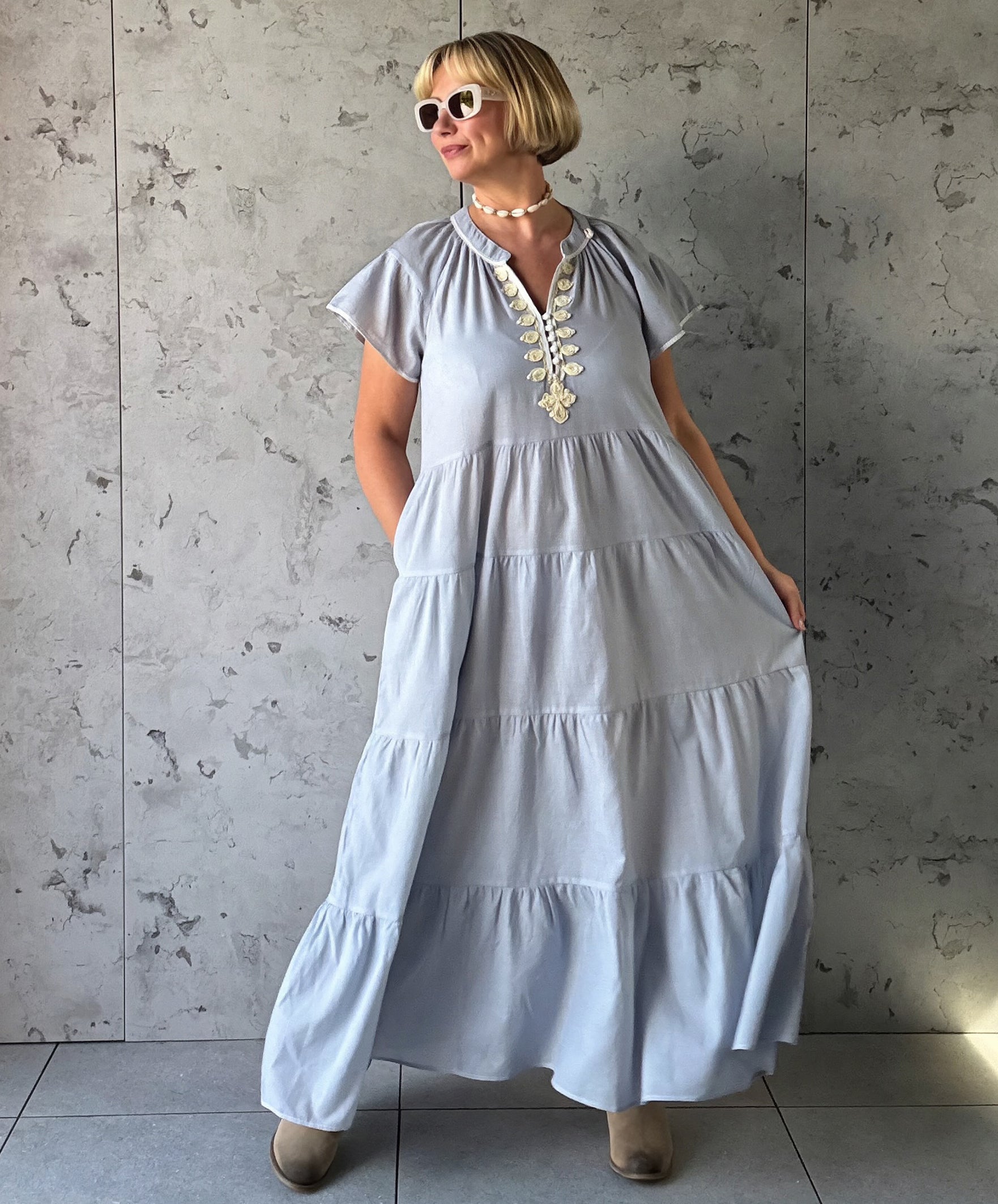 Woman wearing a long blue striped dress with a textured wall background