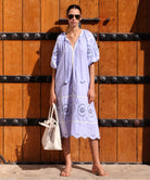 Woman in a light blue dress standing in front of a large wooden door.