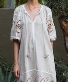 Natural linen dress with embroidery on sleeves and neckline against a natural background