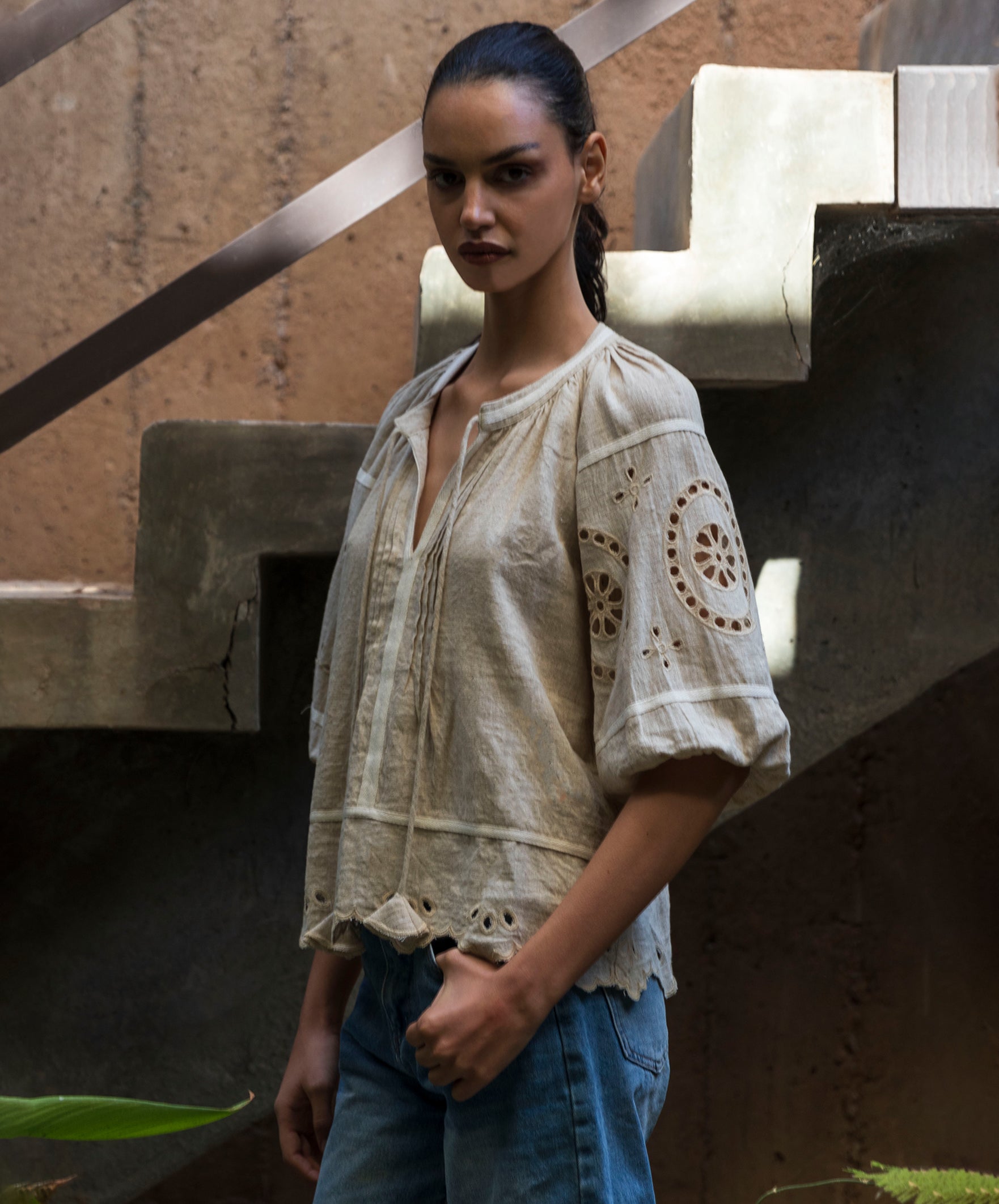 Woman wearing a natural linen blouse with intricate embroidery in an urban setting