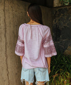 Back view of a model wearing a Rose and Rose Newbury embroidered top in pink. 