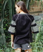 Back view of a model wearing a Rose and Rose Newbury embroidered top in black.