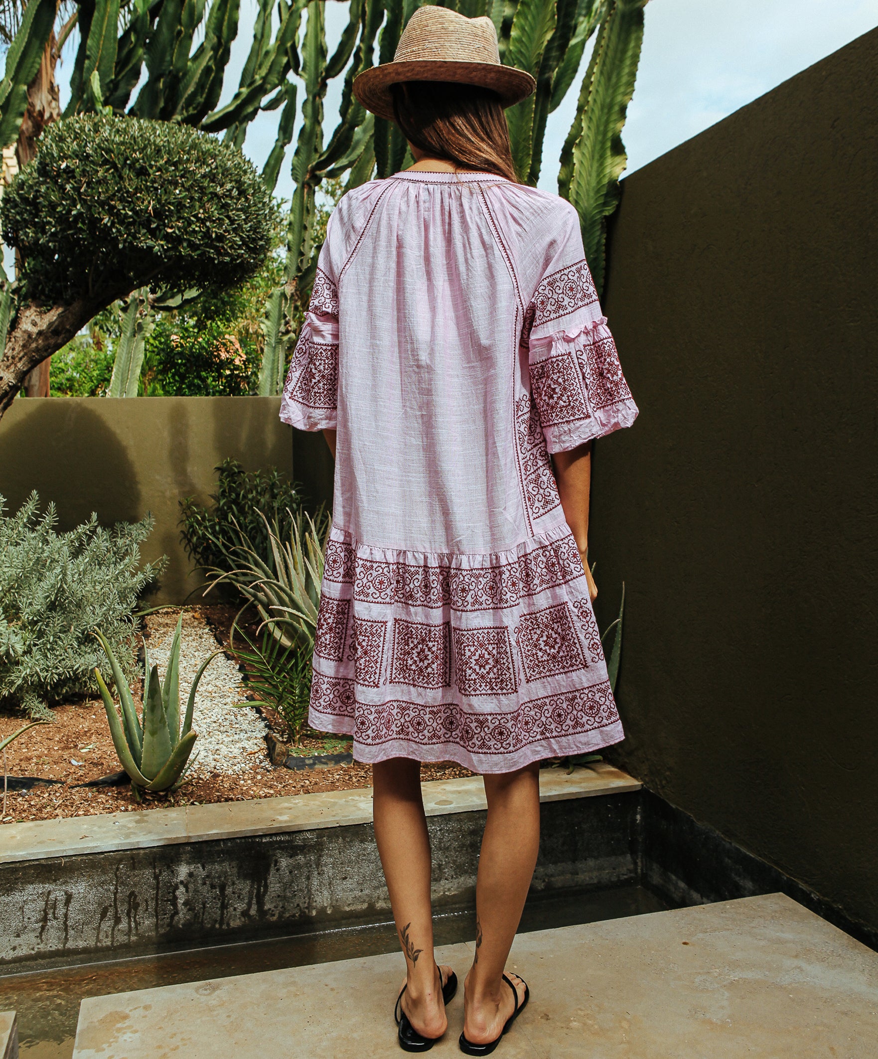 Back view of a model wearing a Rose and Rose embroidered Notting hill pink dress. 