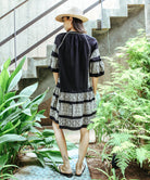 Back view of a model wearing a Rose and Rose embroidered Notting hill dress in black cotton.