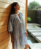 A model wearing a Rose and Rose Oxford dress in marl blue with white appliqué decoration.