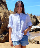 A model stood on the beach wearing a pale blue embroidered Parma top with denim shorts. 