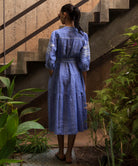 Woman in a blue dress chambray standing on a staircase with plants around