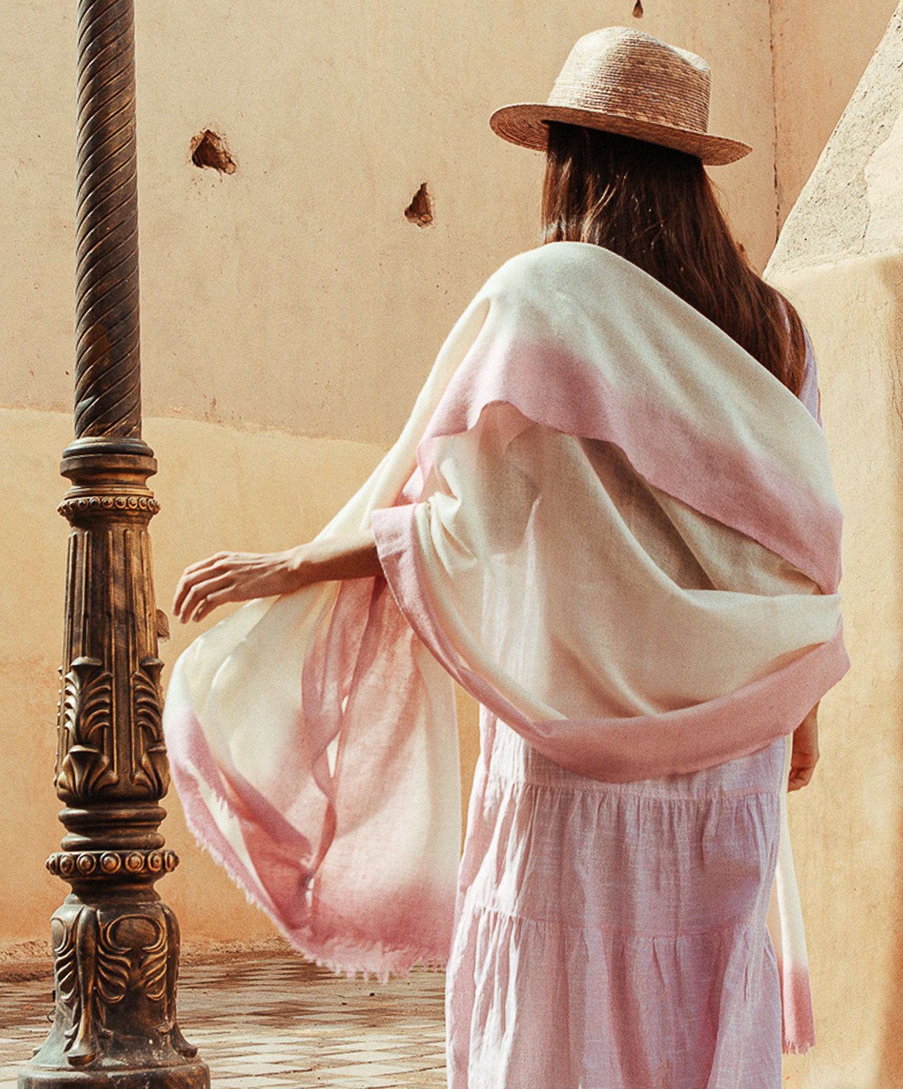 A back view of a model wearing a Rose and Rose cashmere wrap draped around her shoulders. 