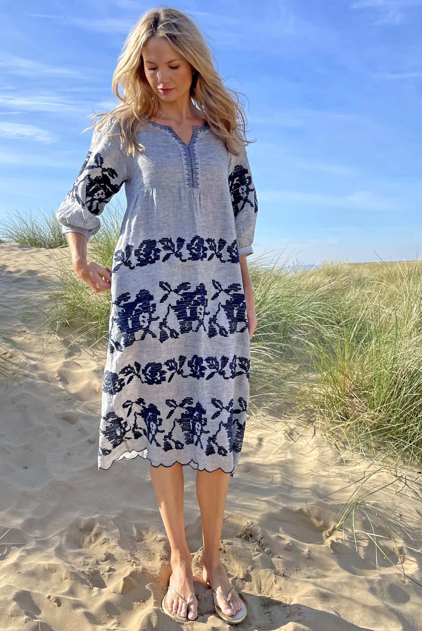 A model stood in sand dunes wearing a Rose and Rose striped linen Portafino dress.