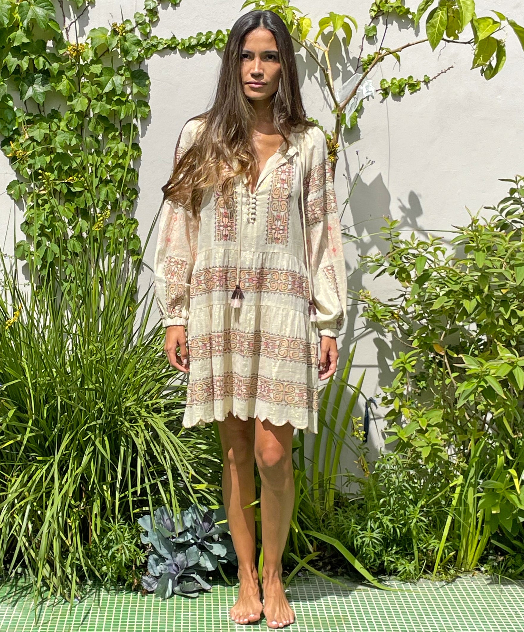 A model in a garden wearing the Rose and Rose Ravello gold lurex embroidered dress.