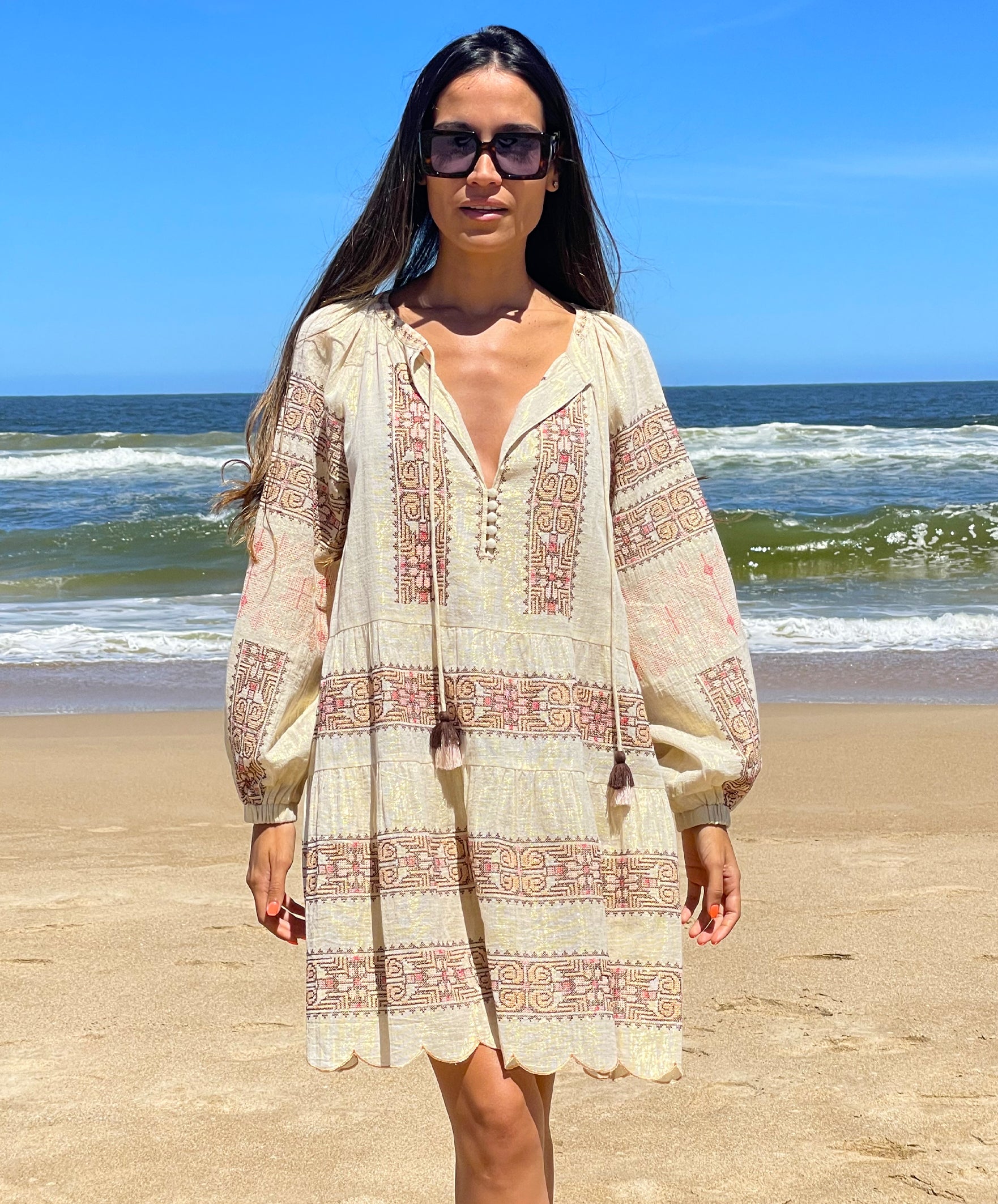 A model on a beach wearing the Rose and Rose Ravello gold lurex embroidered dress.