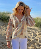 A model on a beach wearing the Rose and Rose Roma gold lurex embroidered top. 