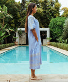 Side view of a model wears a Rose and Rose embroidered Royal Oak dress in blue cotton.