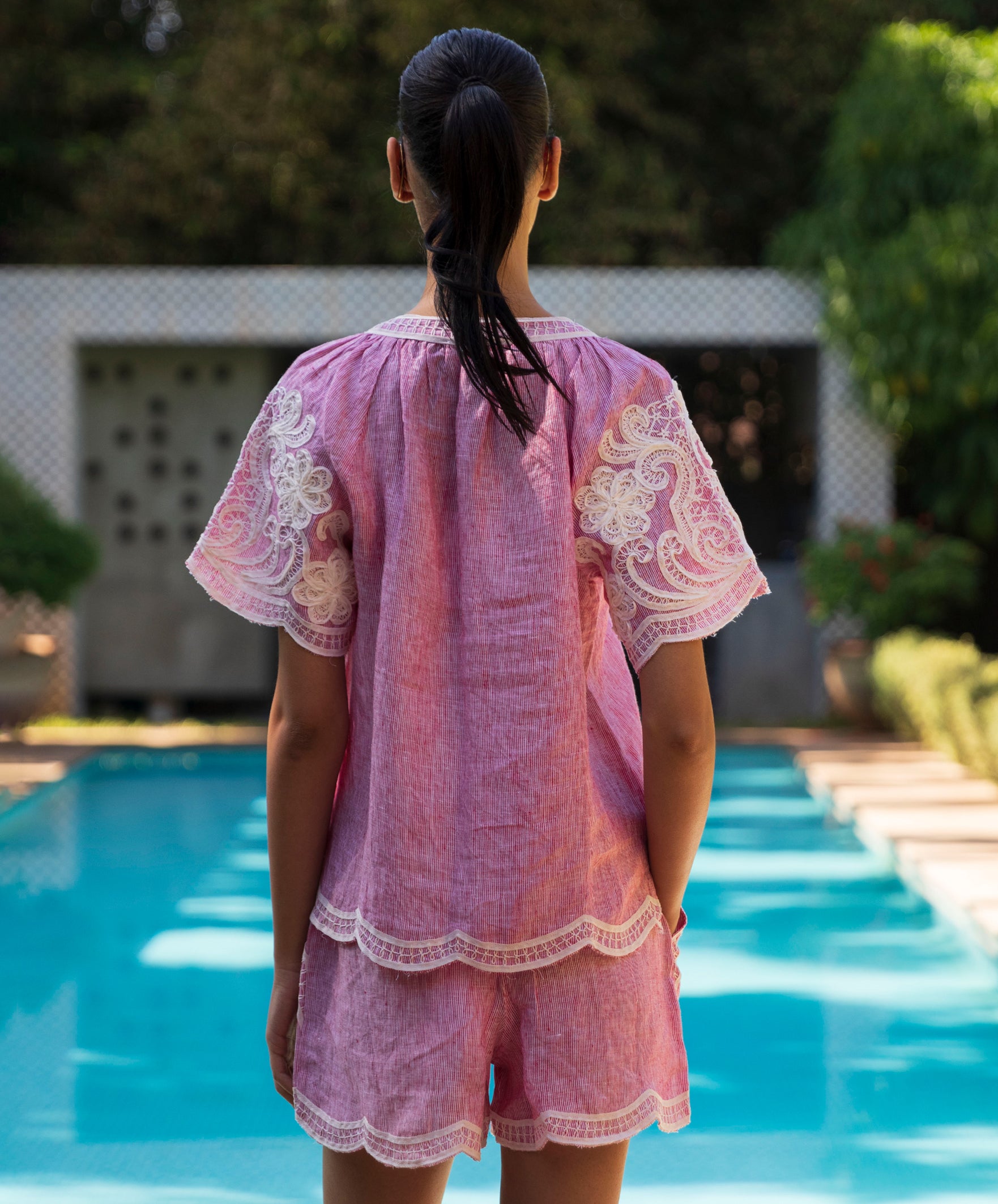 Women wearing a red striped Azalea top and matching shorts with tape decoration by a pool
