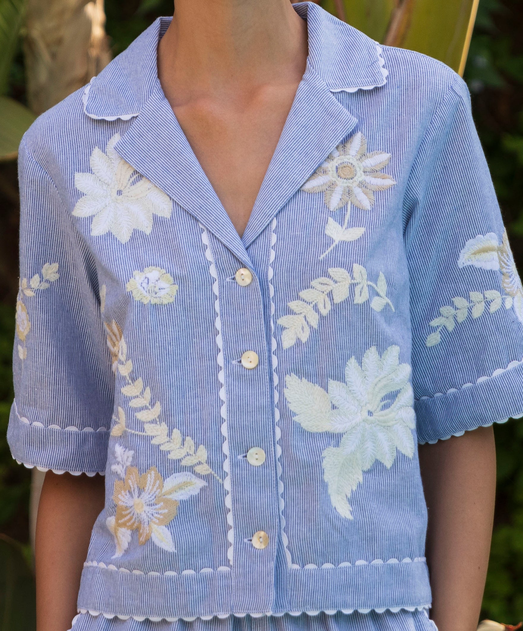 Floral embroidered short-sleeve shirt in blue stripes on a woman