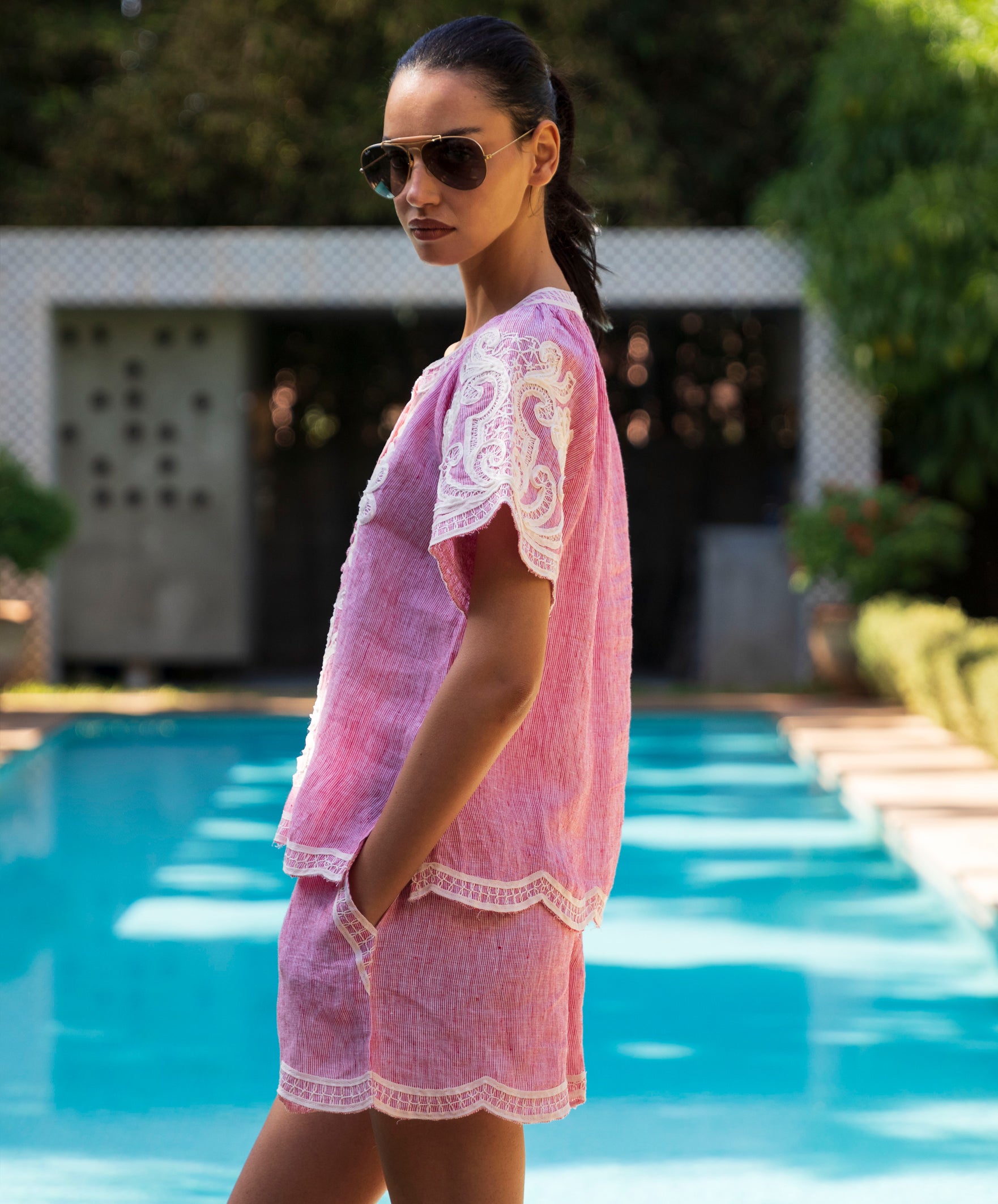 Woman in a red striped Azalea top and matching shorts standing by a pool