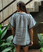 Back view of a model wearing a Rose and Rose Upminster passementerie decorated top in striped linen.