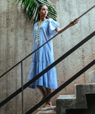 A model wearing a Rose and Rose Uxbridge midi dress with white passementerie decoration. 