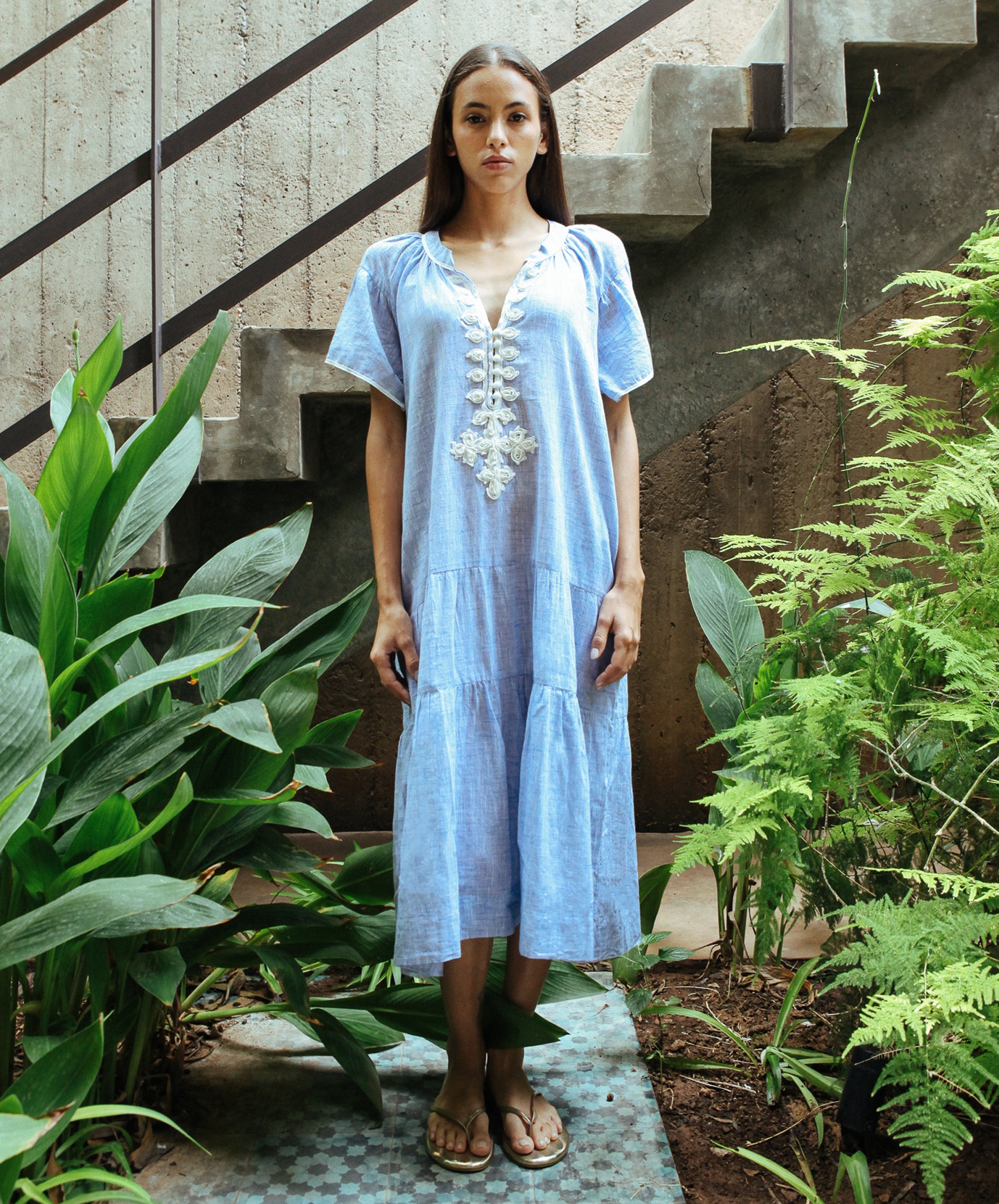 A model wearing a Rose and Rose Uxbridge midi dress with white passementerie decoration. 