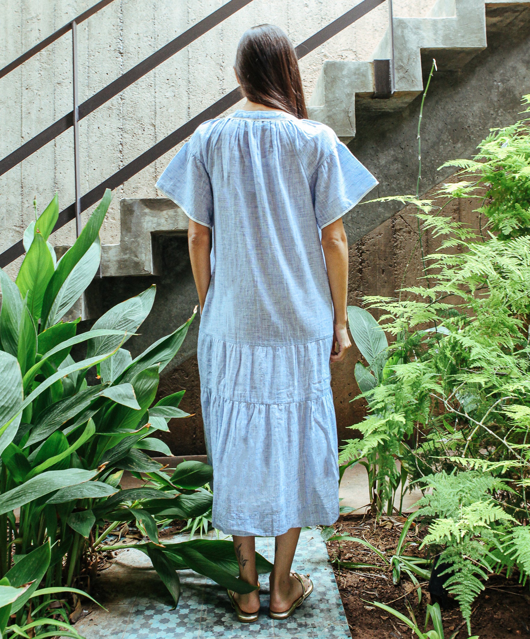 A back view of a model wearing a Rose and Rose Uxbridge midi dress with white passementerie decoration. 