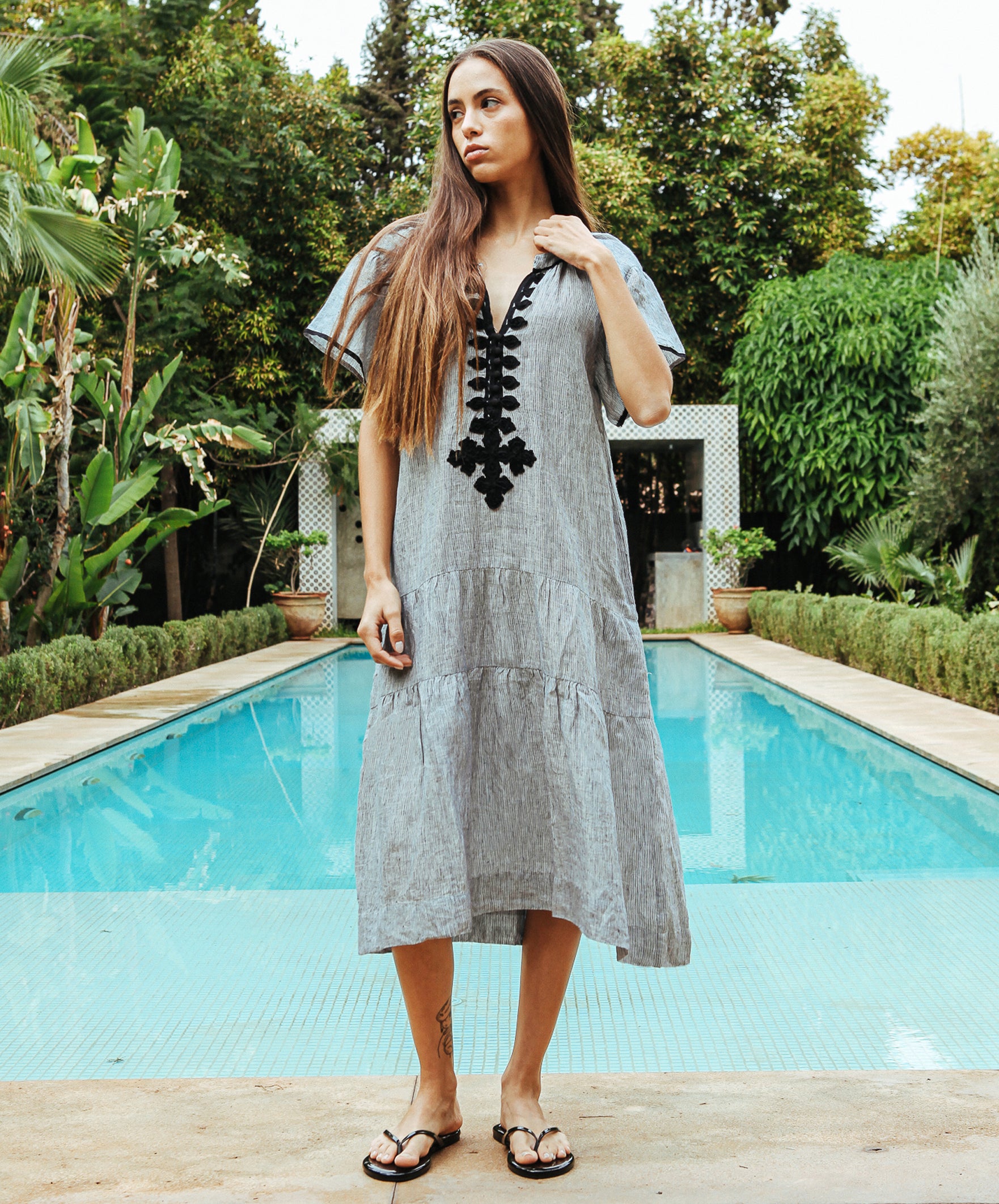 Model wears a Rose and Rose Uxbridge passementerie decorated midi dress in striped linen.