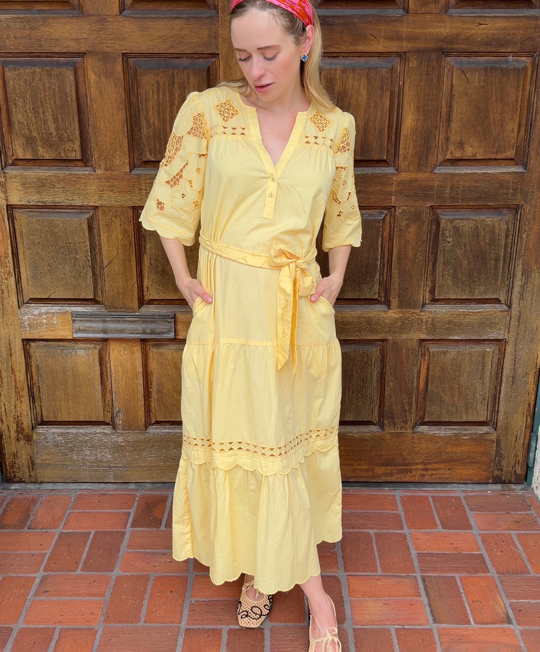Influencer @viktoria_myr wearing the Dahlia dress in pale yellow in front of a wooden doorway. 