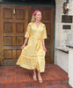 Influencer @viktoria_myr wearing the pale yellow Dahlia dress outside an entrance door. 