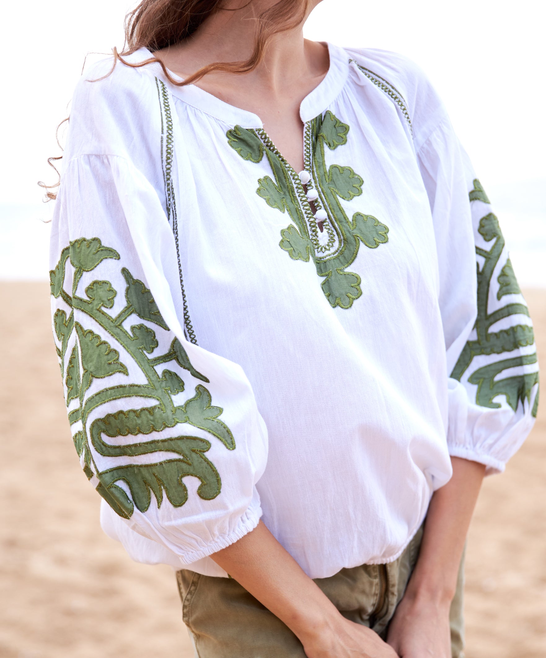 Close up of a premium white cotton top with olive green appliqué motifs, and olive shorts.